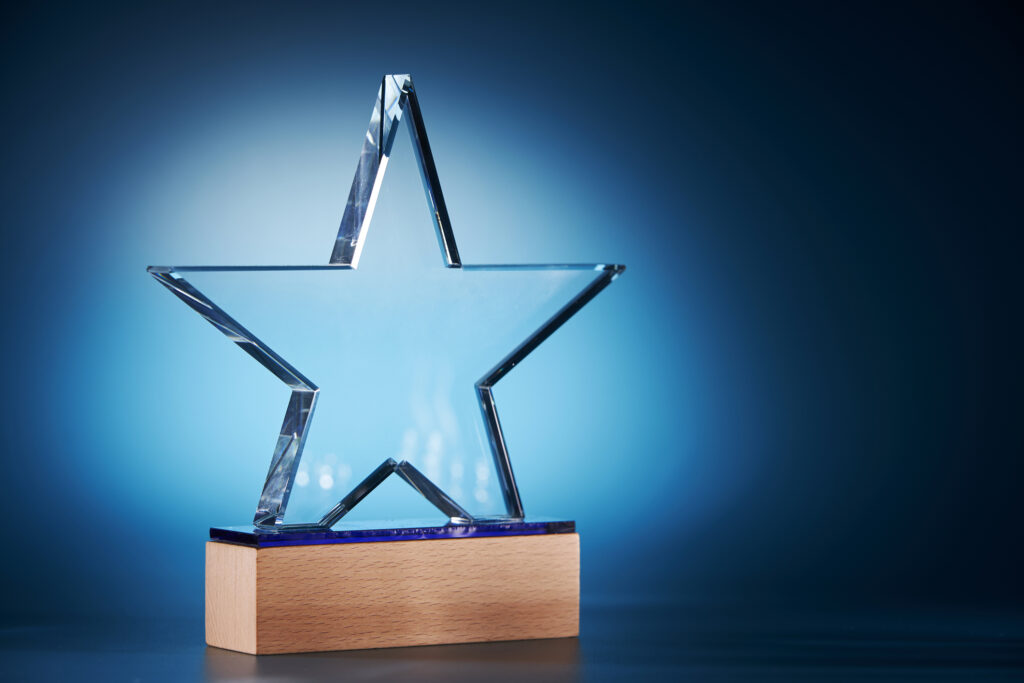 A shinny clear star award photographed with a blue background